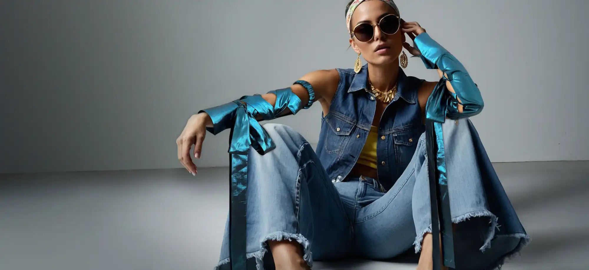 Distressed denim outfit with metallic blue accents worn in a fashion-forward pose.